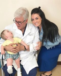 Dr. Arno Fried holding young patient successfully operated on for spinal bifida