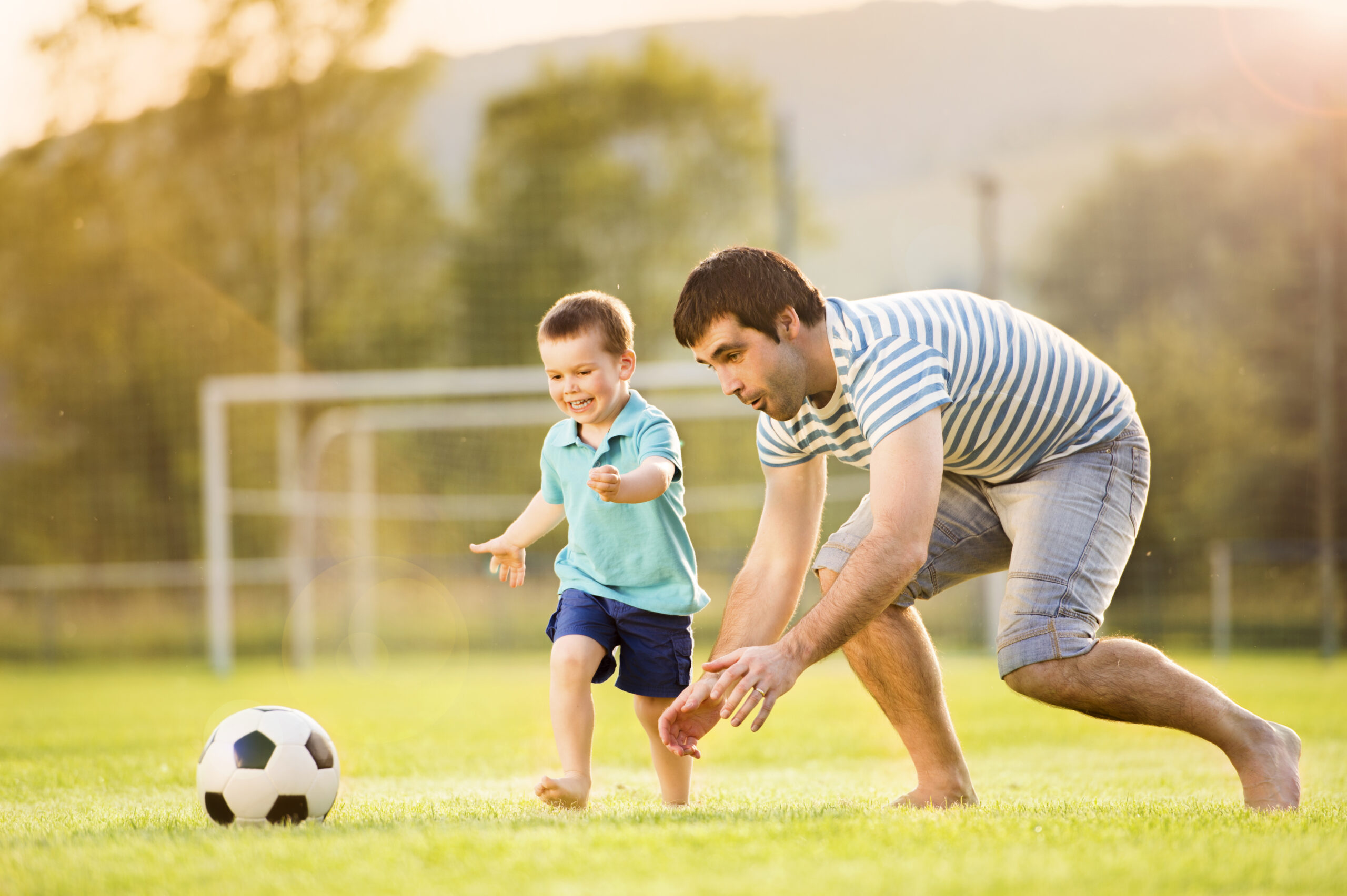 Young,Father,With,His,Little,Son,Playing,Football,On,Football